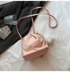 Dettaglio borsa a secchiello rosa con design a pieghe e ciondolo a pompon bianco morbido