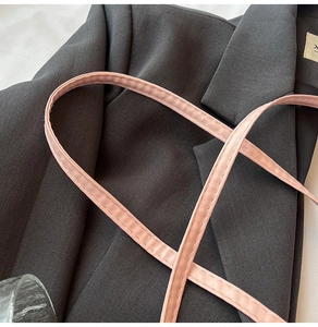Dettaglio della tracolla in pelle rosa con grana fine e cuciture per borsa a secchiello
