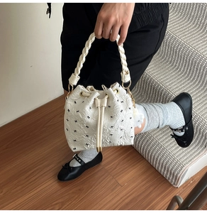 Détail du sac seau blanc à cordon avec imprimé nœud et poignée tressée
