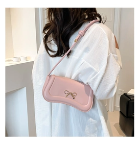 Detail of pink bow shoulder bag with gold metal buckle and knotted strap on model