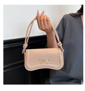 Detailed view of apricot shoulder bag featuring a decorative golden bow and elegant knot handle