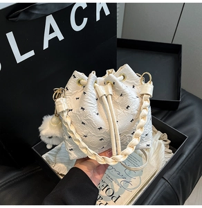 Dettaglio della borsa a secchiello bianca con fiocchi neri e ciondolo di peluche
