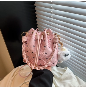 Détail du sac seau plissé rose avec imprimés nœuds noirs et breloque pelucheuse