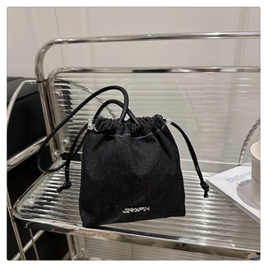Détail d'un sac seau en denim noir avec logo JINGPIN en métal sur une étagère moderne