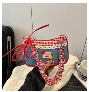 Close-up of denim underarm bag with red plaid trim, lace edges and sweet cherry patch
