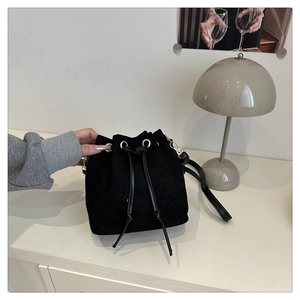 Detail of black corduroy bucket bag with drawstring closure and golden metal hardware