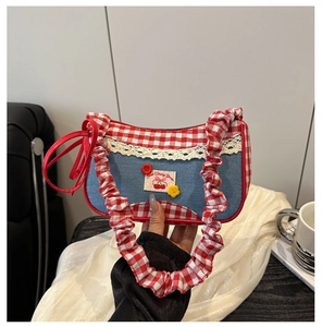 Close-up of red plaid handle and lace trim on a blue denim sweet cherry handbag
