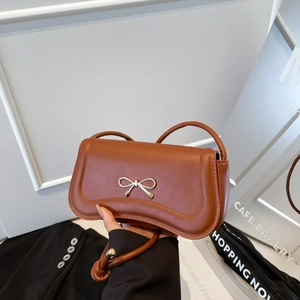 Caramel brown leather shoulder bag with metallic bow clasp and thin round strap