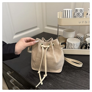 Close-up of beige suede bucket bag with drawstring closure and fine leather strap