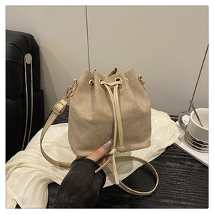 Detail of beige drawstring bucket bag with gold hardware and slim shoulder strap