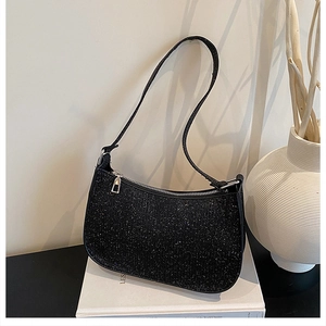 Close-up of a black sequined hobo bag with sparkling finish on a white book