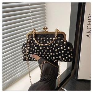 Dettaglio elegante borsa da sera in pizzo nero con perle bianche e manico in metallo oro