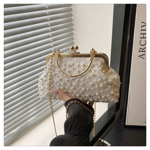 Dettaglio borsa da sera in pizzo bianco con decorazioni di perle e chiusura metallica