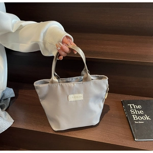 Détail d'un mini sac à main en nylon gris argenté avec étiquette Fashion et anses