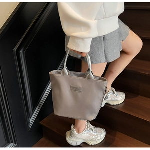 Détail du sac à main en nylon gris avec poignées argentées et écusson FASHION porté