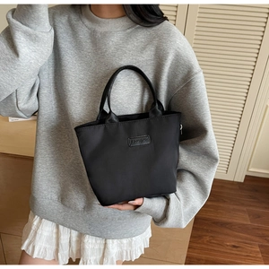 Détail d'un mini sac cabas noir en nylon avec écusson FASHION dans une scène de vie