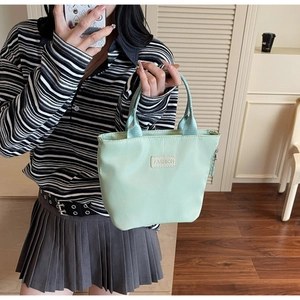 Détail du cabas en nylon vert menthe avec étiquette mode tenu par un mannequin