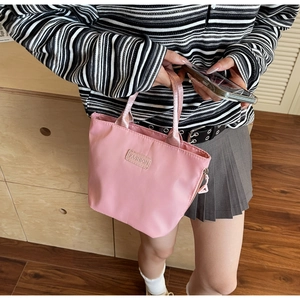 Sac à main en nylon rose avec étiquette FASHION présenté dans un cadre décontracté