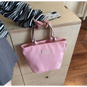 Gros plan détaillé du mini sac en nylon rose avec étiquette mode sur bois