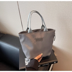 Détail du sac fourre-tout en nylon gris foncé avec étiquette mode et fermeture éclair
