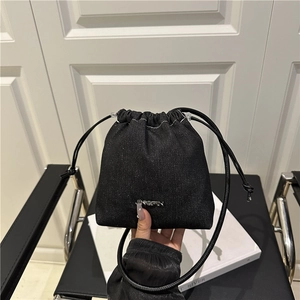 Sac seau minimaliste en jean noir avec cordon de serrage et logo métallique sur le devant