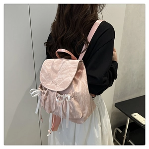Détail du sac à dos rose marbré avec nœuds en satin blanc et broderie Nika élégante