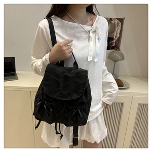 Détail du sac à dos plissé noir avec nœuds en soie latéraux et boucles en métal réglables