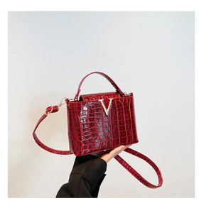 Detailed close-up of red crocodile pattern leather with glossy finish and V-shaped metal buckle