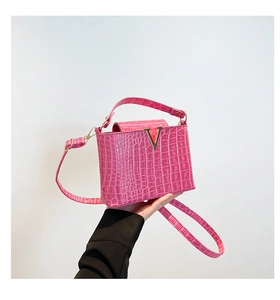 Detailed close-up of bright pink faux crocodile texture with golden V-shaped metal buckle