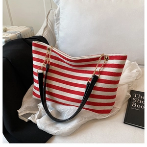 Detail of red and white striped canvas tote featuring herringbone texture and gold chain link