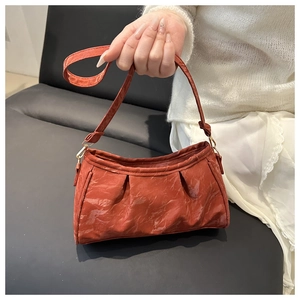 Macro detail of terracotta pleated leather shoulder bag with fine texture and gold hardware