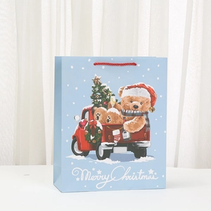 Sac cadeau de Noël bleu clair avec ours en peluche dans un camion et texte festif