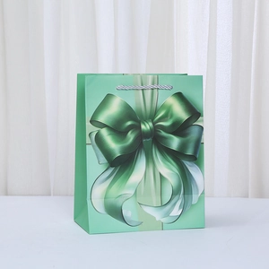 Detalle de la bolsa de regalo verde menta con lazo impreso en 3D y asas trenzadas de plata