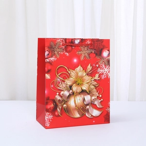 Christmas gift bag in red cardboard with festive floral prints and red rope handles