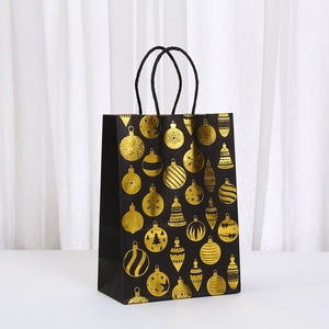 Detail of black matte Christmas gift bag featuring gold foiled holiday ornaments and rope handles