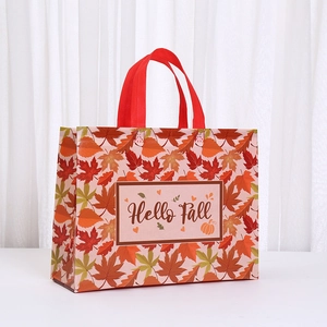 Detail of Hello Fall non-woven gift bag featuring vibrant maple leaf patterns and red handles