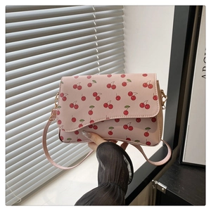 Détail d'un sac demi-lune rose avec des motifs de cerises et des finitions dorées chic