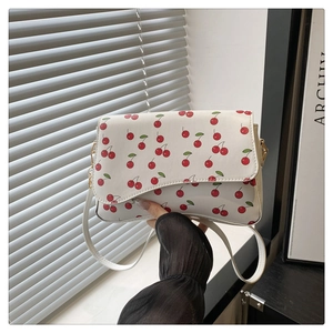 Détail du sac bandoulière blanc avec imprimé cerise rouge et finitions métalliques