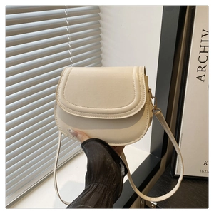 Detail of minimalist cream leather saddle bag showing fine stitching and flap texture