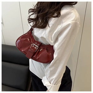 Detail view of burgundy crescent bag with glossy patent leather finish and silver hardware