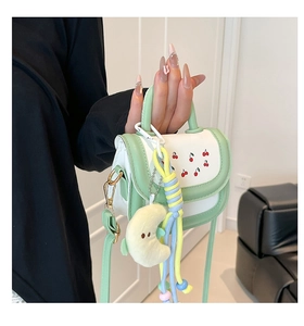 Detail of green and white girls handbag with cherry print and moon plush charm decoration