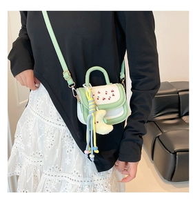 Detail of sweet green crossbody bag with cherry print and moon plush charm