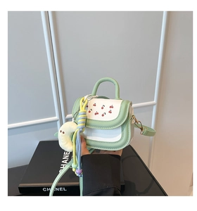 Detail of girl's green and white handbag with cherry print and plush crescent charm