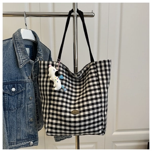 Close-up of black and white checkered tote bag with handmade metal plaque and dog charm