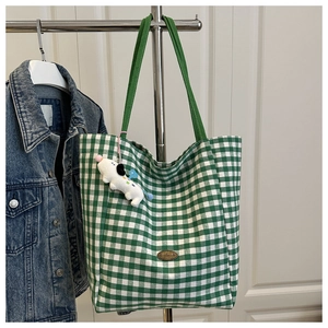 Detail of green plaid canvas tote with handmade leather tag and puppy plush charm
