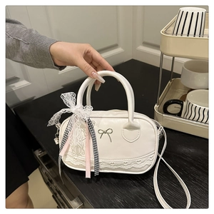 Detail of white bowling bag with silver bow, heart lace trim and ribbon tassels