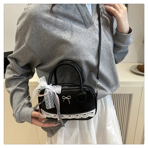 Detail of black bowling bag featuring lace trim, silver bow and ribbon charms