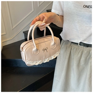 Close-up of pink glossy Boston bag with metal bow and white lace heart trim detail