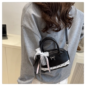 Detailed view of black mini Boston bag with lace bow and silver butterfly pendant detail