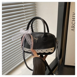 Detail of black bowling bag featuring white heart lace trim and ribbon bow decoration